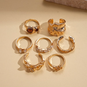 Detail of 7-piece gold alloy ring set with lava textures, amber stones and white beads
