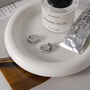 Close-up of silver square hoop earrings with cubic zirconia on a ceramic tray