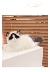 Detailed side view of a fluffy ragdoll cat plush toy with blue eyes on a white stand