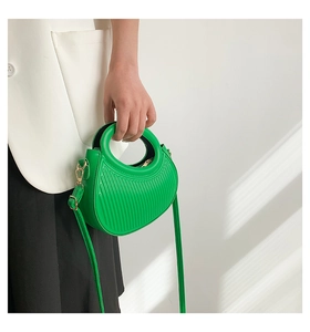 Detail of emerald green crescent bag showing unique vertical pleated texture and golden hardware