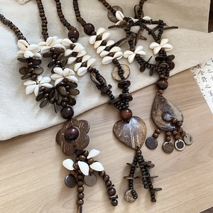 Detail of bohemian handmade necklace with coconut shell, wood beads and shell flower pendant