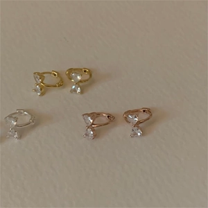 Detailed view of bow-style heart earrings in gold, silver, and rose gold finishes