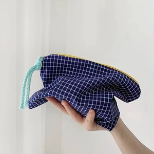 Detail of checkered makeup bag with yellow zipper and light blue cord puller
