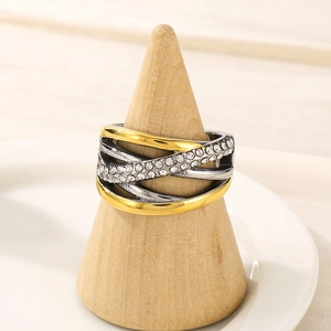 Détail de bague bicolore entrelacée avec cristaux sur support en bois