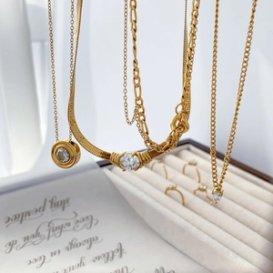 Gold layered necklaces with teardrop cubic zirconia pendants on white jewelry box display
