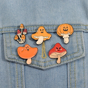 Close-up of five Halloween mushroom enamel pins styled on a denim jacket pocket
