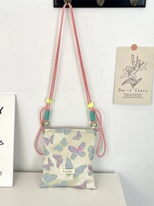 Artistic cream crossbody bag with purple butterfly patterns and pink woven strap