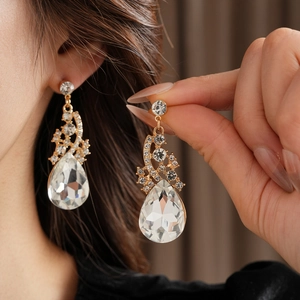 Gros plan de boucles d'oreilles dorées en cristal poire avec petits diamants