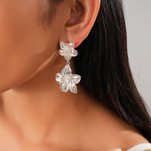 Close-up of a floral silver earring with metallic texture worn by a model in profile