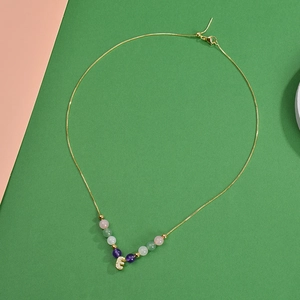Gros plan du collier de perles rhodochrosite 6mm avec pendentif lettre E doré zircon