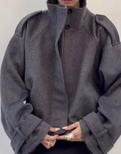 Detail of dark gray wool oversized jacket featuring high collar and shoulder epaulettes