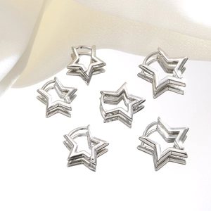 Detailed close-up of six silver star earrings set on a mirror with silk fabric background