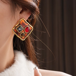 Gros plan de boucles d'oreilles vintage dorées avec pierres de couleur sur un mannequin