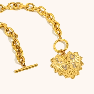 Detail of 18K gold heart pendant with radial texture and LOVE text on chunky chain