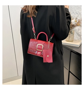 Détail du sac à main bordeaux motif crocodile avec boucle dorée et mini pochette