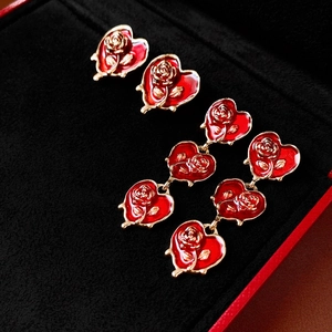 Retro luxury heart earrings with red enamel roses and golden frames on black velvet