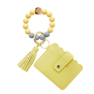 Detail of yellow PU leather card holder with silicone bead bracelet and tassel keychain