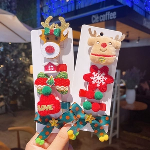 Close-up of Christmas hair clips featuring plush reindeer, knit hats, and sequin bows