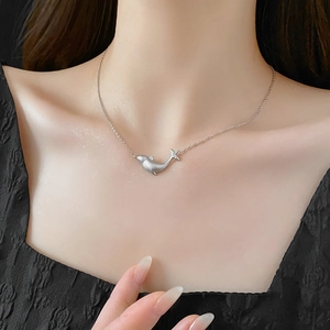 Close-up of minimalist silver whale pendant necklace with zircon inlay on neck