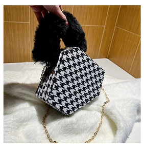 Detail of hexagonal houndstooth bag with black faux fur handle and gold chain strap