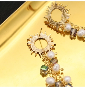 Macro detail of sunburst drop earrings with freshwater pearls and iridescent crystals