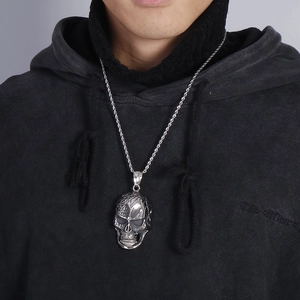 Detailed close-up of a punk skull pendant necklace with intricate patterns on a twist chain