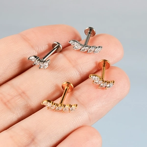 Détail de piercings labret en acier inoxydable doré et argenté avec cinq zircons marquises