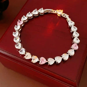 Détail du bracelet cœur avec zircons roses et blancs sur support en bois rouge