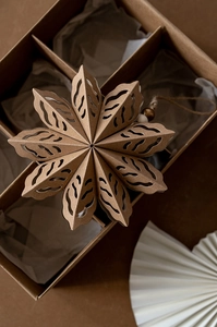 Detail of kraft paper snowflake ornament with wooden beads on natural gift box