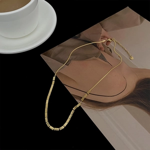 Detail of gold snake chain necklace with rectangular metal blocks on fashion magazine