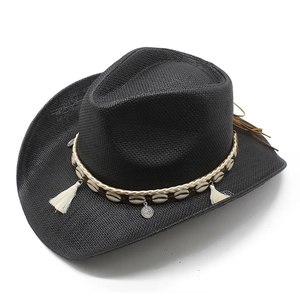 Chapeau de cowboy tissé noir avec bandeau en coquillages et glands bohèmes sur fond blanc