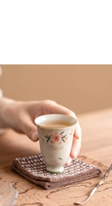Detail of hand-painted pink floral patterns on high-foot ceramic teacup for tea ceremony