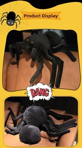 Detailed view of a large black plush spider toy with red eyes on a brown leather sofa