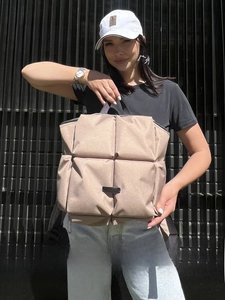 Gros plan d'un sac à dos matelassé beige avec motifs carrés et poches latérales