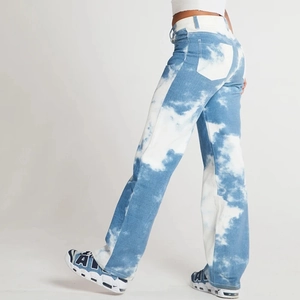 Detail view showing slim fit denim jeans with blue and white cloud pattern from side back