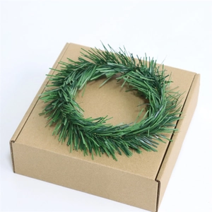 Mini green PVC pine needle Christmas wreath candle ring displayed on a brown box