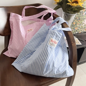 Grandi borse tote in tela a righe rosa e blu su una sedia con fiori di girasole