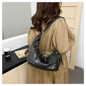 Detail of black vintage hobo bag with gold rivets and wide strap on trench coat