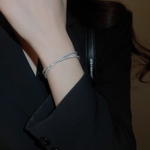 Détail d'un bracelet en argent avec zircons croisés sur un mannequin en costume noir
