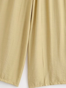 Gros plan sur la texture en lin beige et le drapé du pantalon large pour femmes