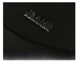 Close-up of black wool cap fabric with JEANS metal tag and refined sewing details
