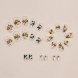 Short press-on nails featuring vintage yellow flowers and green leaf silhouette patterns