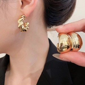 Detailed view of chunky gold hoop earrings featuring twisted rope and smooth metal finishes