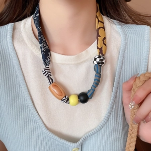 Gros plan sur le collier pendentif cœur en tissu et bois porté par un mannequin femme