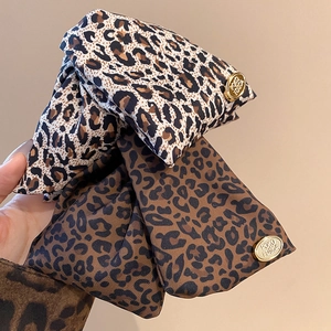 Close-up of leopard print fabric hair clips with gold metal buckles and fine texture