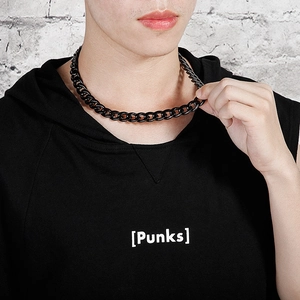 Close-up of a chunky black stainless steel Cuban link chain necklace on a male model