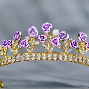 Detail showing golden rose crown with purple flowers, rhinestones and a white pearl