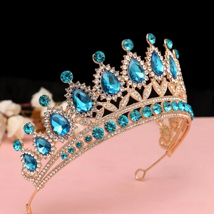 Dettaglio corona barocca dorata con cristalli blu a goccia e motivi a foglia ornati