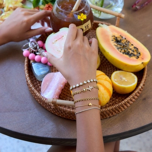 Luxurious layered gold bracelet set with zircon hearts and pulse charms on a wrist