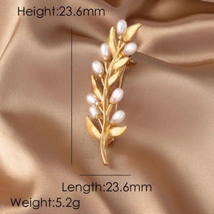 Detail view of pearl wheat brooch with matte gold finish on elegant satin background
